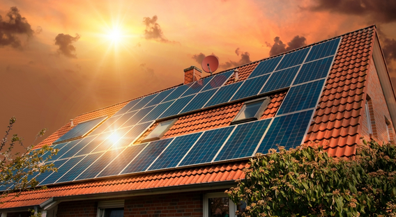 Solar panels atop a house in Jaipur, Rajasthan, capture the vibrant hues of sunset, symbolizing the shift to renewable energy and solar energy. 