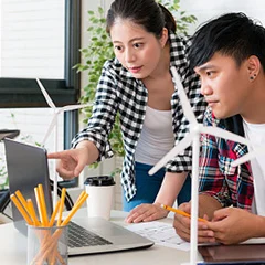  Two team member focus on a laptop, with planing solar energy  in view, representing the integration of technology and renewable energy